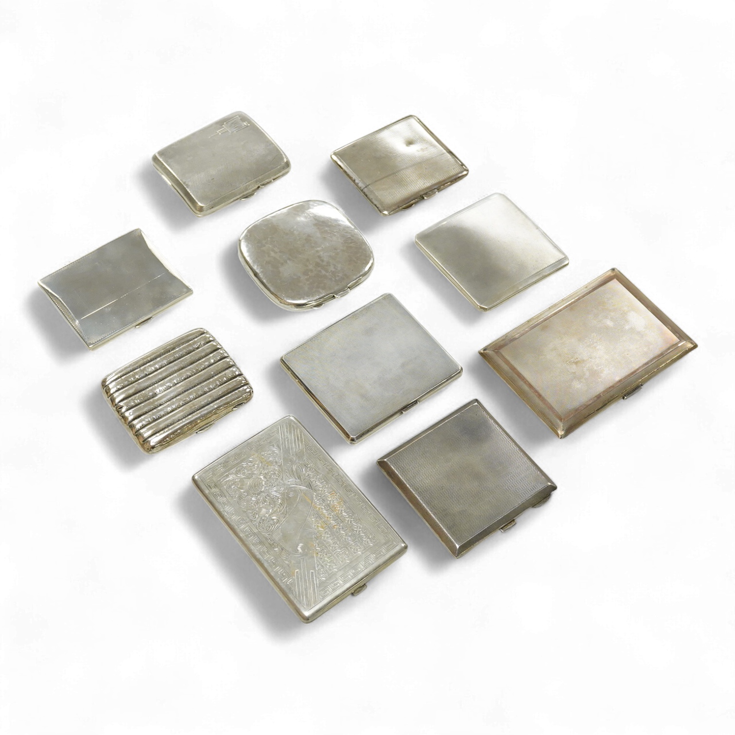 Nine assorted silver cigarette cases, including an Edwardian ribbed case and an engine turned rectangular case by Garrard & Co, Birmingham, 1960, 12.7cm, 32.1oz and one other unmarked white metal cigarette case.